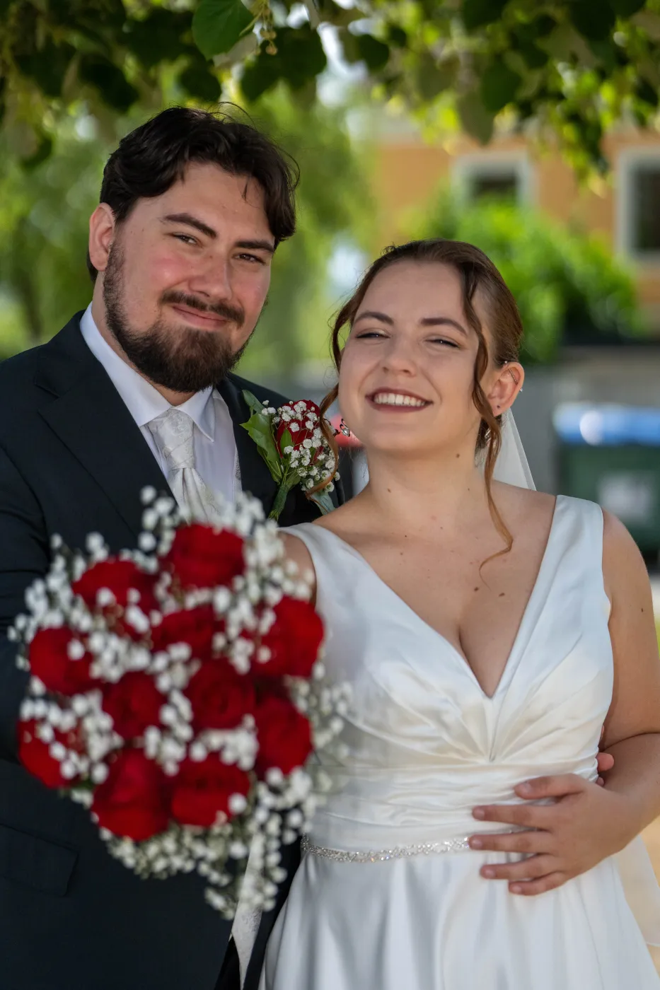Brautpaar lacht, Brautstrauß aus roten Rosen